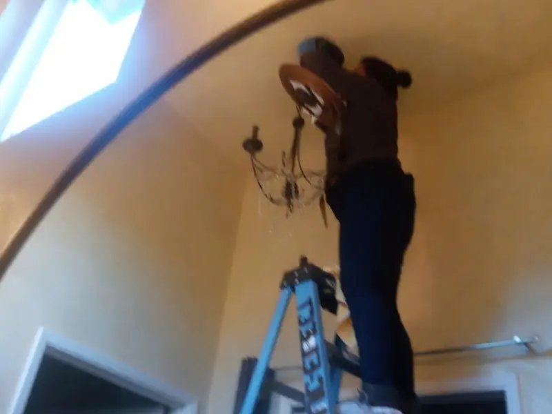 Electrician installing a chandelier in a Tuttle residence